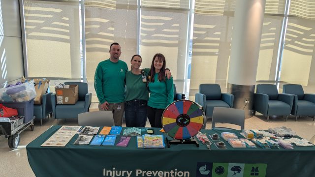 Michael Pirtle, Karissa Reynolds, and Amanda Abramczyk-Thill ran an outreach table with activities to include 'Medicine or Candy?', 'Clear the Crib,' and Spin-the-Wheel to answer a question about child safety.
